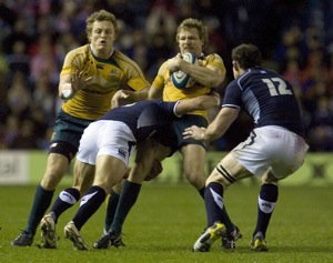 Australia's Peter Hynes, center, is tackled by Scotland's Alex Grove 